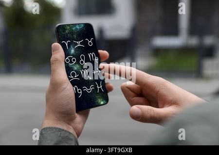 Man using astrology app on his smartphone outdoors, closeup Stock Photo