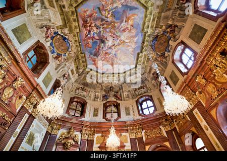 Low angle view of a painted allegorical ceiling, gilded stucco, red marble pilasters and crystal chandeliers in an 18th-century palace interior. Stock Photo