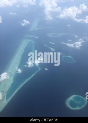 Aerial view of the Maldives showcasing a cluster of small coral islands surrounded by turquoise waters. The islands are scattered across the dark blue Stock Photo
