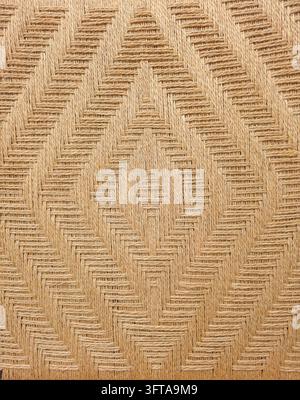 Full frame background texture of handwoven natural beige jute rope creating an intricate geometric diamond and herringbone pattern. Features detailed Stock Photo