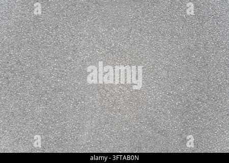 Asphalt road surface showing a uniform grey texture composed of small aggregate stones, ideal for backgrounds or demonstrating material quality in urb Stock Photo