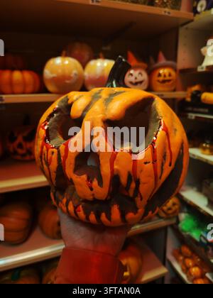 Orange plastic pumpkins on a store shelf ahead of Halloween,capturing spooky seasonal shopping spirit Stock Photo
