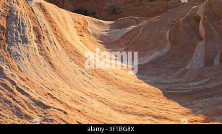 View of the unique sandstone rock formations at Valley of Fire State Park with vibrant orange and white layers illuminated by golden hour light in Moa Stock Photo