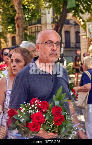 A middle aged man with glasses carries a large red rose bouquet among participants in the street. Stock Photo