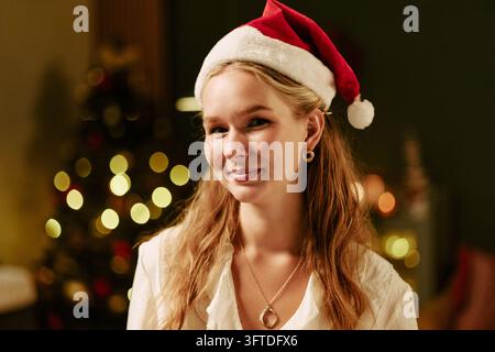 Portrait of Woman Wearing Santa Hat Smiling at Christmas Celebration Stock Photo