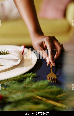Black Woman Setting Table with Golden Cutlery for Holiday Dinner Stock Photo
