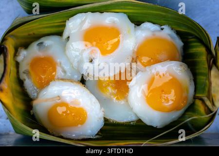 Fried quail egg In the container made of banana leaves is a street food in local market in Thailand, close up. Thai food Stock Photo