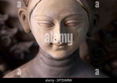 Macro view of a smooth clay goddess face with carved eyelids and a gentle smile in the Kumartuli district, West Bengal, Kolkata, India Stock Photo