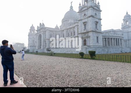 Visitor holding up a phone to photograph a white marble memorial with domes and towers, West Bengal, Kolkata, India Stock Photo