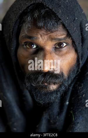 Frontal headshot of a man with a thick grey beard and dark eyes with head covered by a black wool cover, West Bengal, Kolkata, India Stock Photo