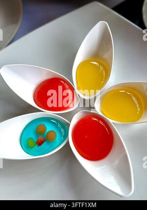 Top view of five colorful Indonesian traditional desserts in white ceramic spoons arranged as flower on white plate Stock Photo