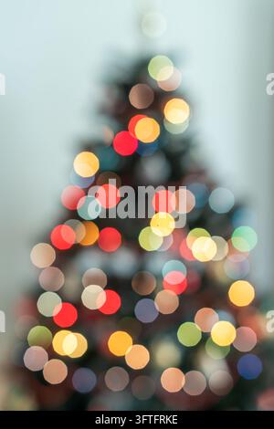 Christmas tree silhouette surrounded by beautiful warm and cool defocused lights on a soft light blue background, with generous copy space for holiday Stock Photo