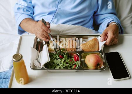 Middle Aged Man Eating Balanced Meal in Hospital Bed Stock Photo