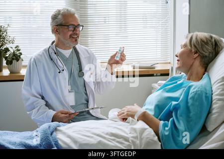 Middle Aged Male Doctor Showing Medication to Patient in Hospital Stock Photo