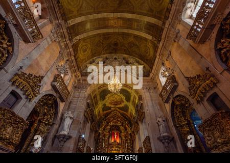Wide Angle Low Angle View of the Main Nave with Gilded Baroque Altars, Crystal Chandeliers, and Vaulted Ceiling inside Carmo Church in Porto, Portugal Stock Photo