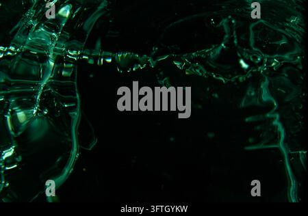 429.high-angle, close-up photograph of a liquid surface, showing ripples and a splash frozen in time.The image has a dark background with striking gre Stock Photo