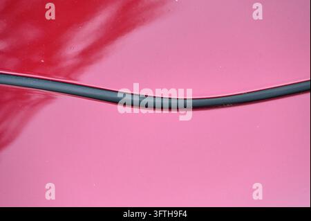 showcasing an extreme close-up of a glossy red vehicle panel with a clean paint finish, reflection, and narrow panel gap. Stock Photo