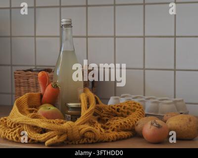 Reusable crochet mesh bag with fresh vegetables, apples and glass bottle, eco-friendly Stock Photo