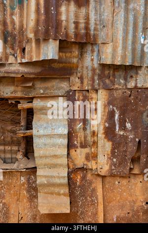 Close-up of a wall patched together from rusty corrugated iron sheets with a small window frame in Kibera, Nairobi County, Nairobi, Kenya Stock Photo