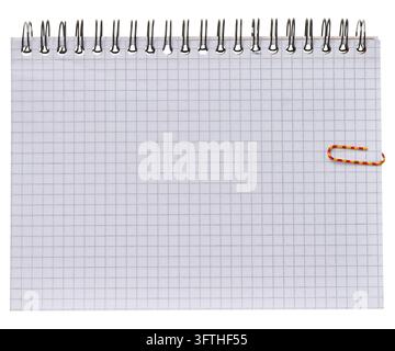 A sheet of squared paper from a spiral-bound notebook with a colored paperclip on the side, isolated background. Stock Photo