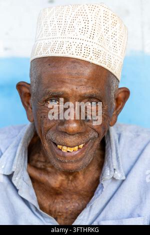 Portrait of a smiling elderly man with deep wrinkles wearing an embroidered white kofia cap and a light blue shirt, Jambiani, Tanzania Stock Photo