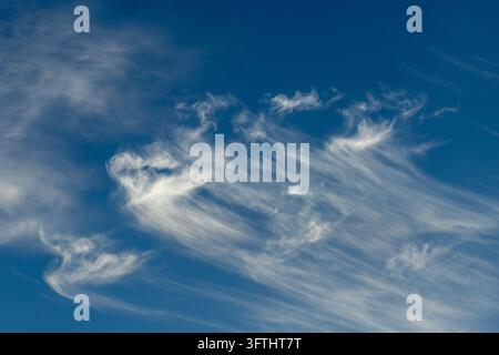 Delicate featherlike cirrus clouds spreading across a deep blue sky Stock Photo