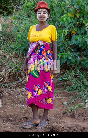Smiling young woman wearing a traditional clay face mask and a colorful wrap skirt, Menabe, Tsiribihina, Madagascar Stock Photo