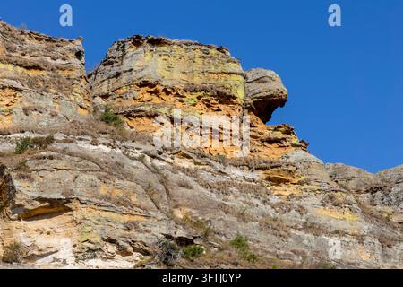 Close-up of the weathered sandstone cliff of Isalo covered in yellow and grey lichen against a clear blue sky, Ihorombe, Isalo, Madagascar Stock Photo