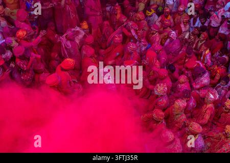 High angle view of a packed crowd of turbaned celebrants and a billowing cloud of pink powder at Lathmar Holi, Uttar Pradesh, Barsana, India Stock Photo
