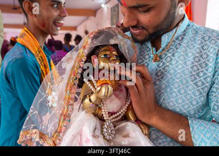 Two young men holding a decorated deity statue during Braj Ki Holi, Uttar Pradesh, Nandgaon, India Stock Photo