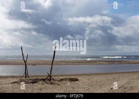 Driftwood sculptures on sandy beach with stormy clouds, Newport Oregon Stock Photo