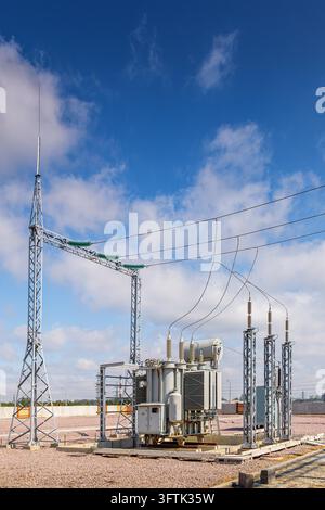 Vertical view of an outdoor electrical distribution substation, without people, at daytime on a background of a clear blue sky Stock Photo