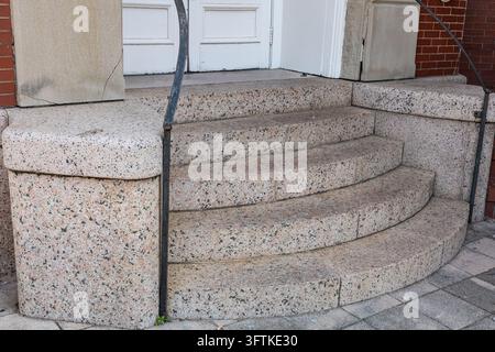 Close-up of curved stone entrance steps with metal handrails leading to white wooden double doors of a historic brick building in Galveston, Texas, US Stock Photo