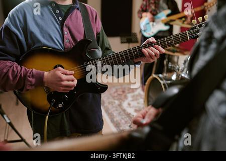 Man Playing Electric Guitar with Band Rehearsing in Studio Stock Photo