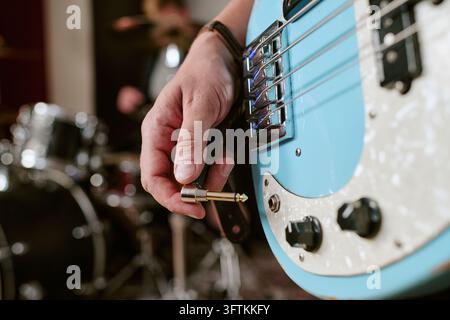 Musician Hand Plugging Audio Jack into Electric Bass Guitar Stock Photo