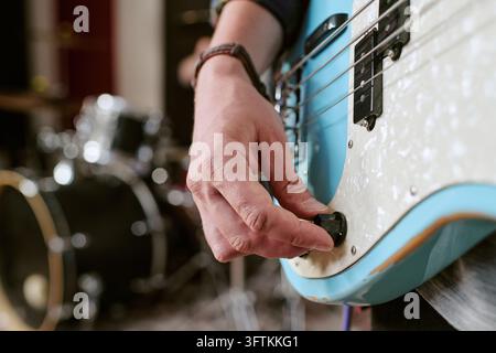 Musician Hand Adjusting Volume Knob on Bass Guitar Stock Photo