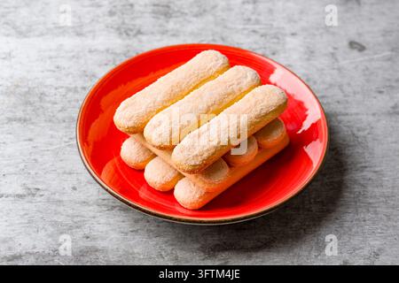 Stacked Savoiardi ladyfinger biscuits served on bright red plate Stock Photo