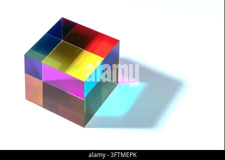 Prismatic cube generating light spectrum with vibrant colors and blue shadow on white background Stock Photo