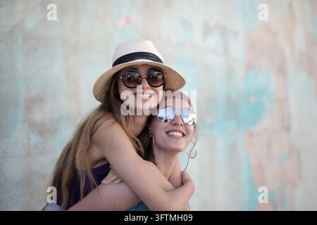 Two happy female friends embracing and smiling outdoors Stock Photo