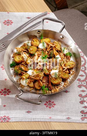 Hearty skillet of roasted potatoes and meat with herbs Stock Photo