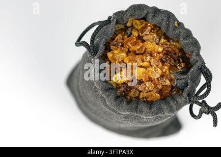 Gray velvet pouch opened to reveal sparkling amber caramel sugar crystals resembling gemstones, a mystery bag concept on clean white background. Stock Photo