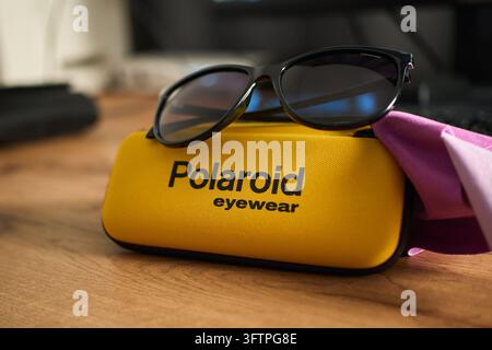 Tyumen, Russia - September 20, 2026: Detailed close up of black Polaroid sunglasses lying on a yellow branded eyewear case with a cleaning cloth on wo Stock Photo