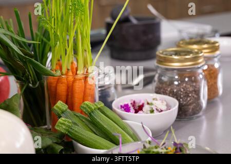 Baby zucchini and fresh carrots in glass jar on kitchen counter Stock Photo