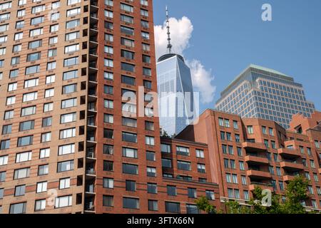 2019 New York City, USA; view of One World Trade Center spire rising behind brick residential buildings and Brookfield Place in Lower Manhattan Stock Photo