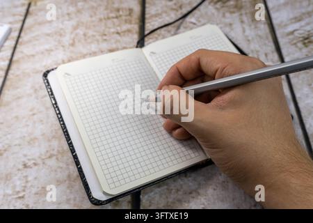 Person writing with pencil in grid paper notebook close up Stock Photo