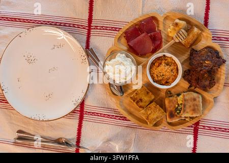 Albania,  : Top down view of a traditional wooden platter filled with various Albanian dishes, including cured meat, cheese, and pie. Stock Photo