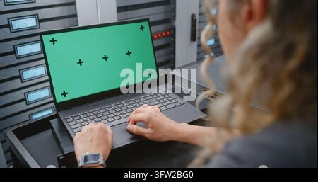 Female IT Specialist Works on Green Screen Laptop Inside Modern Data Center, Offering Customizable Footage for Women in Technology, Cybersecurity, Cloud Infrastructure and Digital Interface Concepts. Stock Photo
