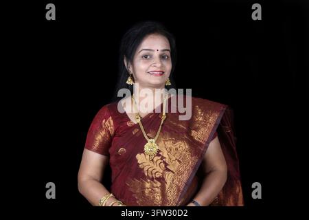 A smiling middleaged Indian woman in a traditional saree, on black studio background Stock Photo
