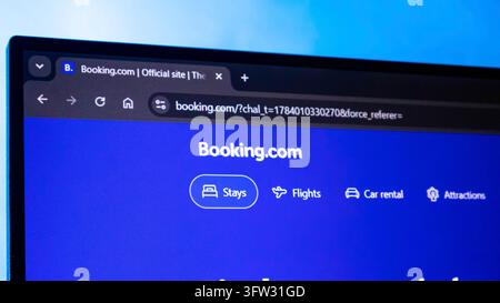 A laptop displays Booking.com's blue travel booking page with options for stays, flights, car rental, and attractions Stock Photo