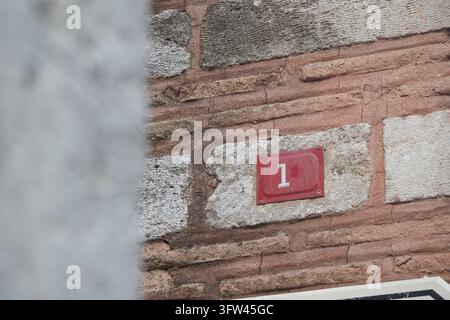 Red number one plaque mounted on a stone and brick wall Stock Photo
